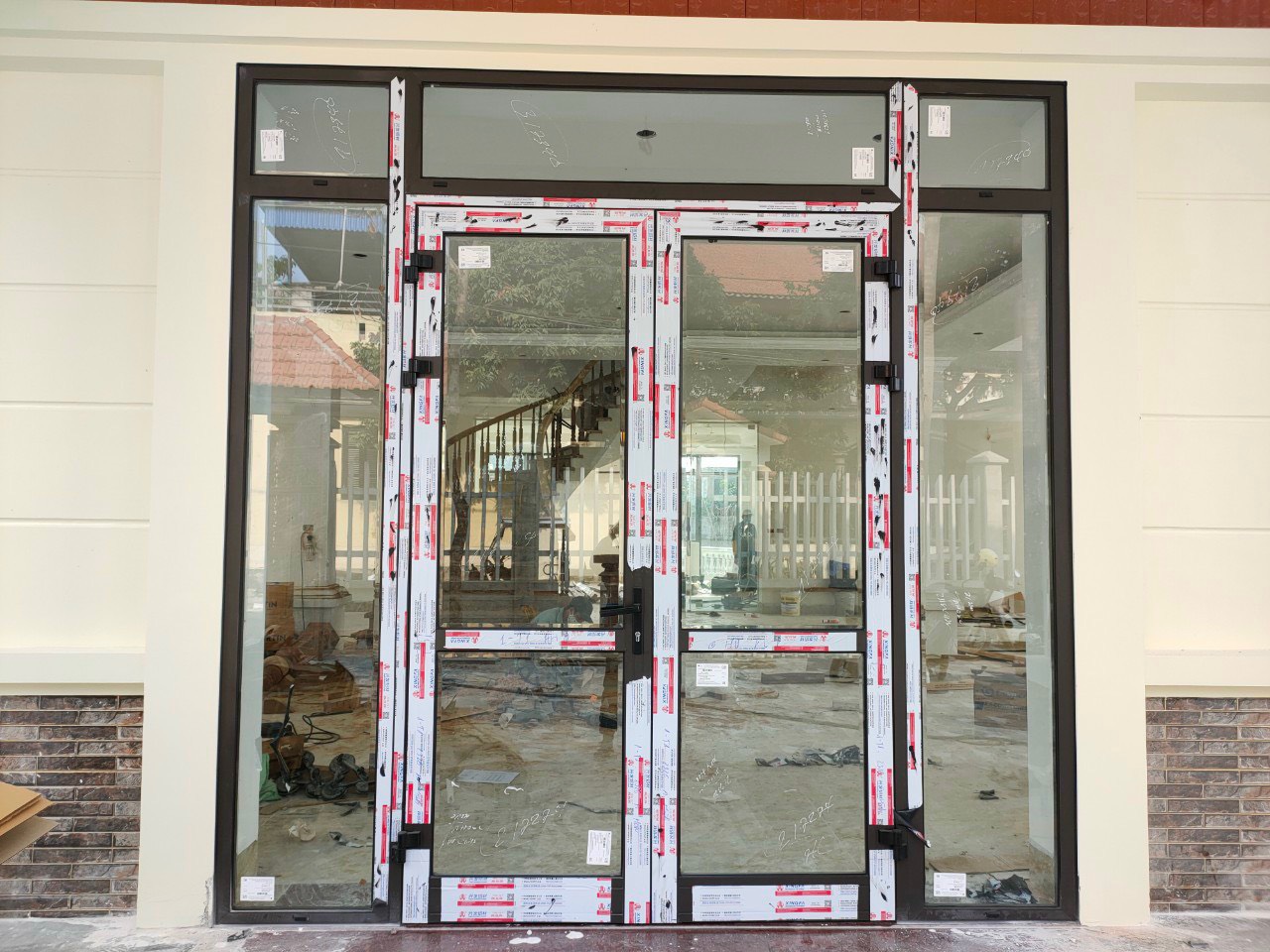 Cửa đi nhôm kính Xingfa 4 cánh đang lắp đặt cho mặt tiền nhà phố